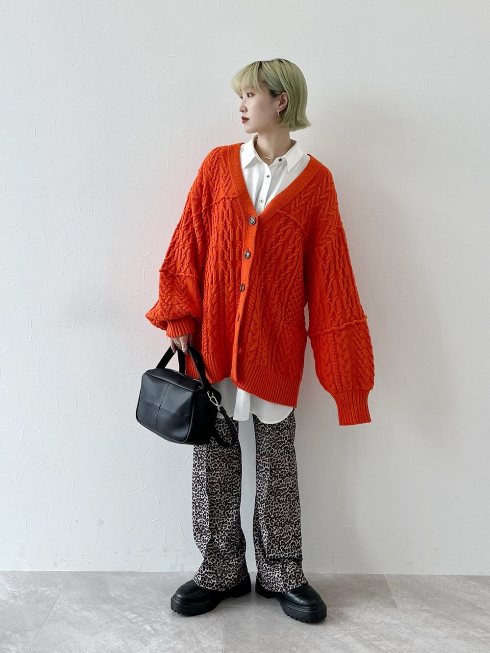 オレンジ系のカーディガン/ボレロ、ホワイト系のシャツ/ブラウス、ブラック系のショルダーバッグを着用したレディースの秋コーディネートの4枚目の写真