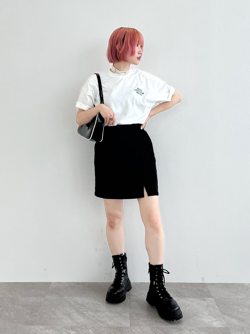 ホワイト系のTシャツ/カットソー、ブラック系のスカート、ブラック系のブーツを着用したレディースの夏コーディネートの2枚目の写真