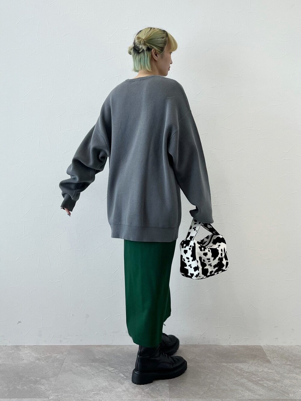 グレー系のニット/セーター、ブラック系のハンドバッグ、グリーン系のスカートを着用したレディースの秋コーディネートの3枚目の写真