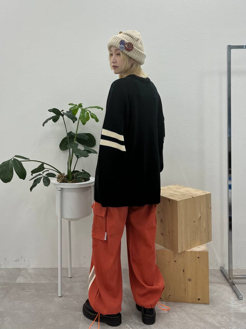 ブラック系のニット/セーター、オレンジ系のその他パンツ、ベージュ系のニットキャップ/ビーニーを着用したレディースの秋コーディネートの2枚目の写真
