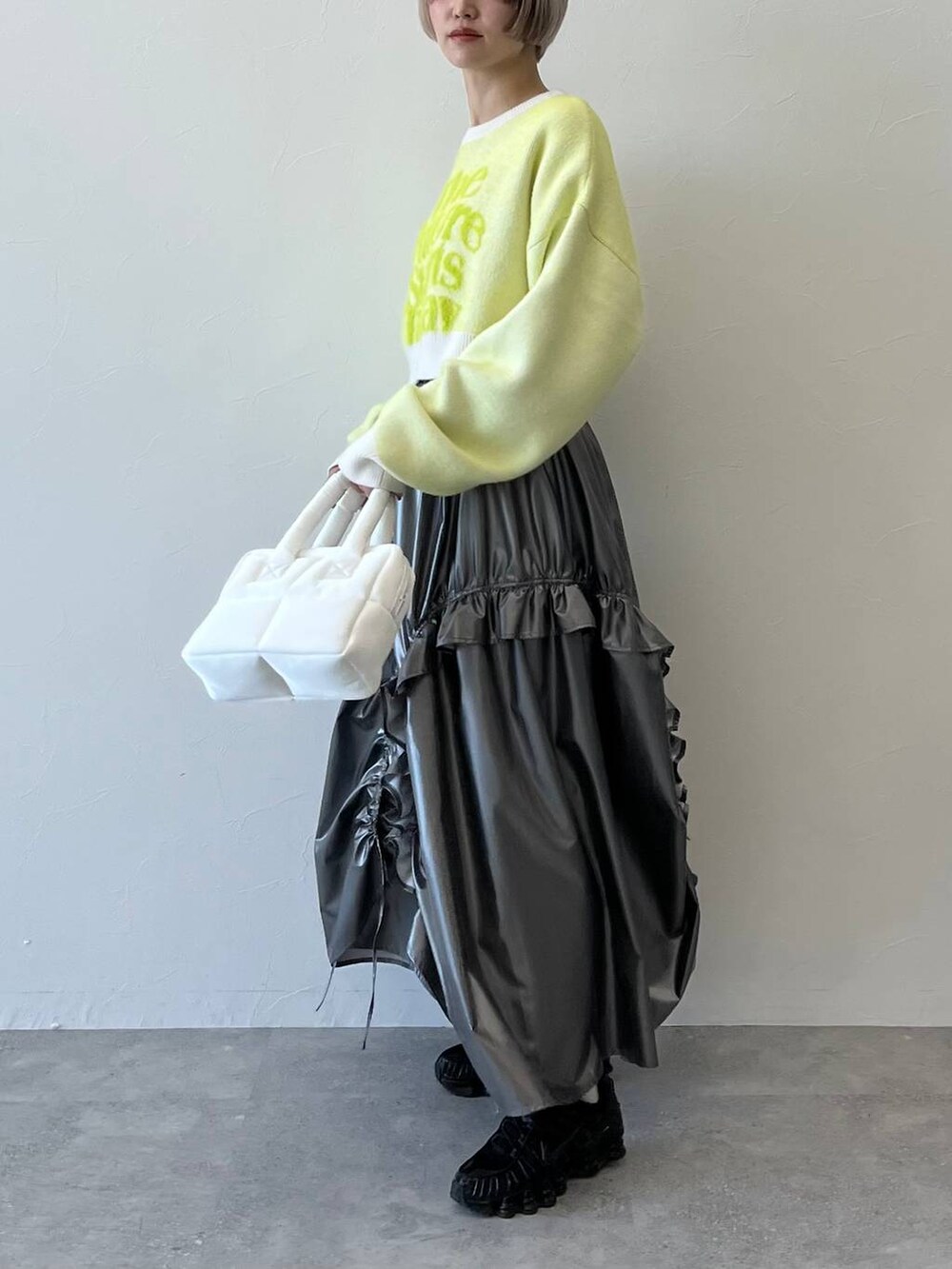 ホワイト系のニット/セーター、ホワイト系のハンドバッグ、シルバー系のスカートを着用したレディースの秋コーディネートの2枚目の写真