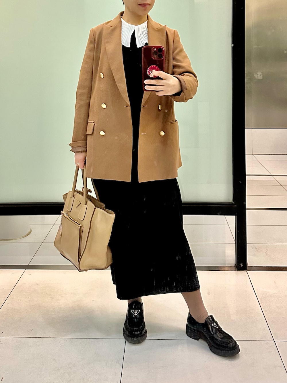 イエロー系のテーラードジャケット、ブラック系のワンピース、ブラック系のローファーを着用したレディースの春コーディネートの2枚目の写真