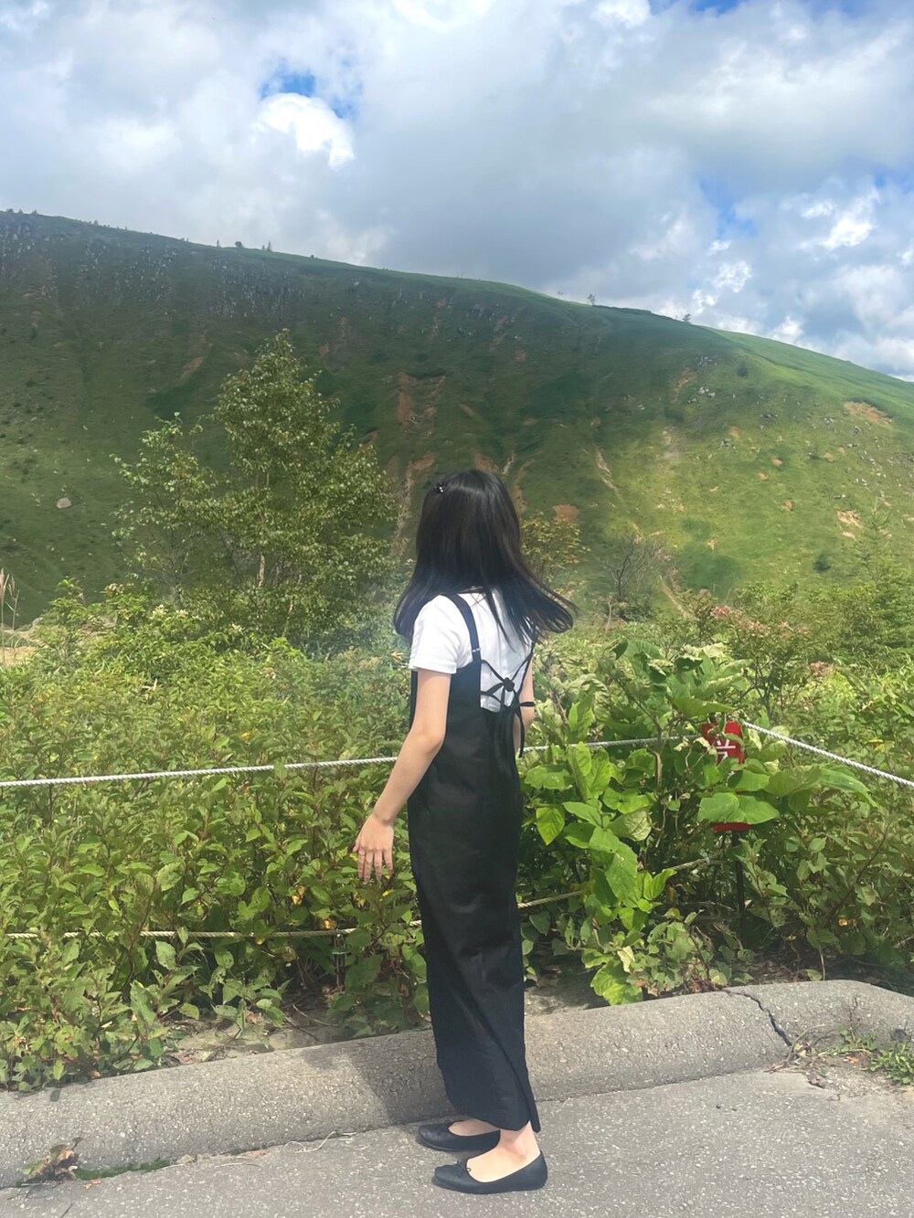 ブラック系のワンピース、ブラック系のバレエシューズ、ホワイト系のTシャツ/カットソーを着用したレディースの夏コーディネートの2枚目の写真