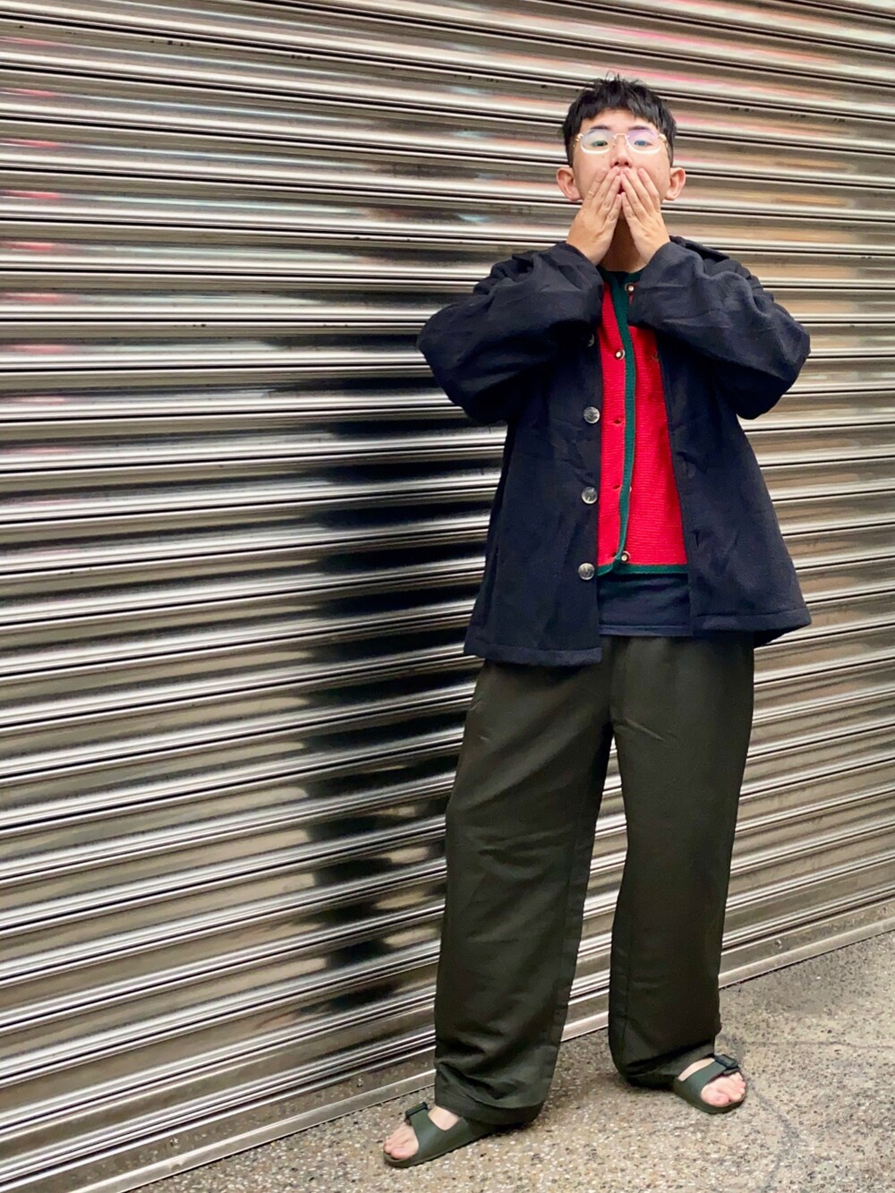 グリーン系のチノパンツ、レッド系のベスト、ブラック系のチェスターコートを着用したメンズの冬コーディネートの2枚目の写真