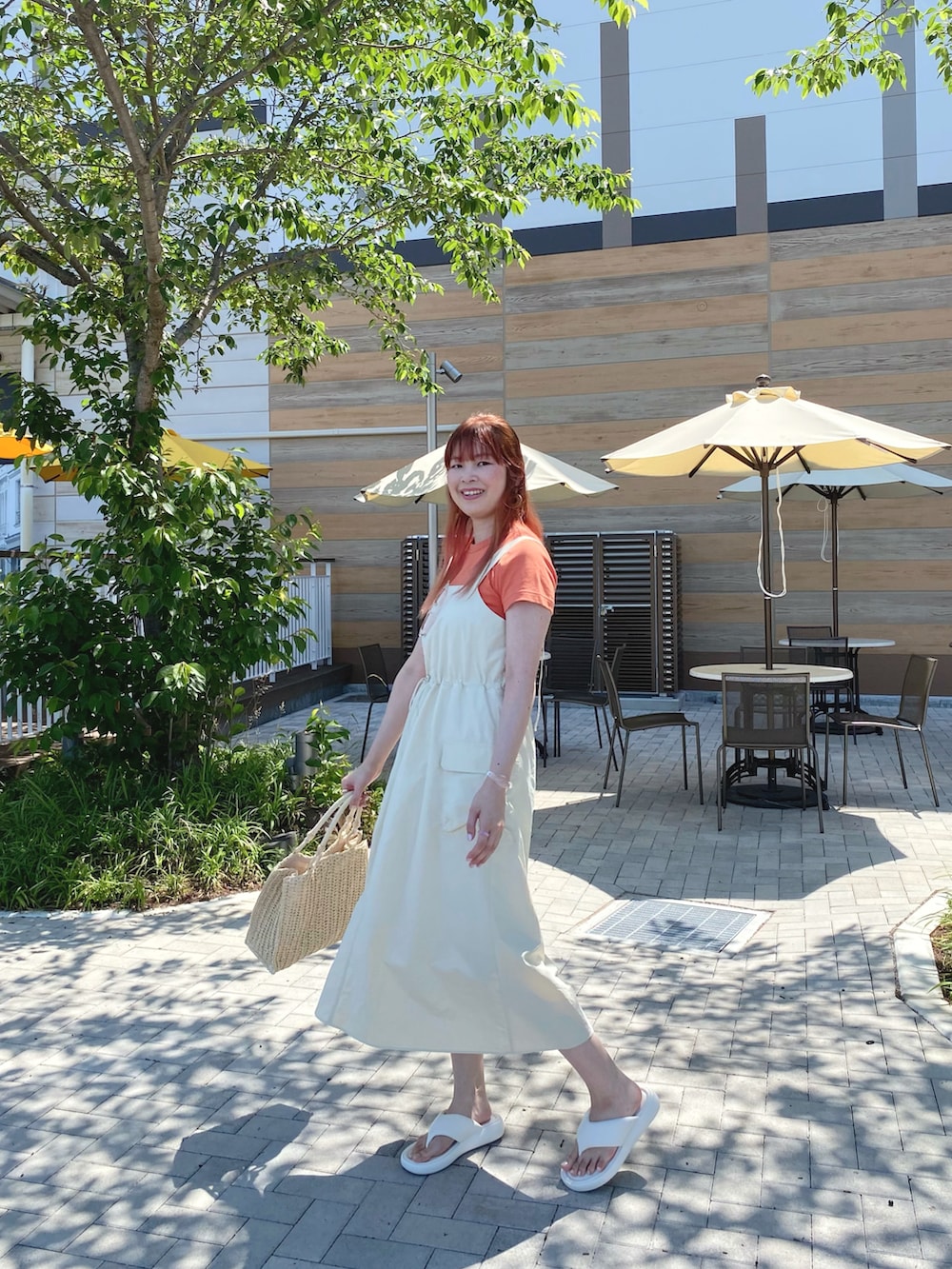 オレンジ系のTシャツ/カットソー、ホワイト系のワンピース、ベージュ系のかごバッグを着用したレディースの春コーディネートの2枚目の写真