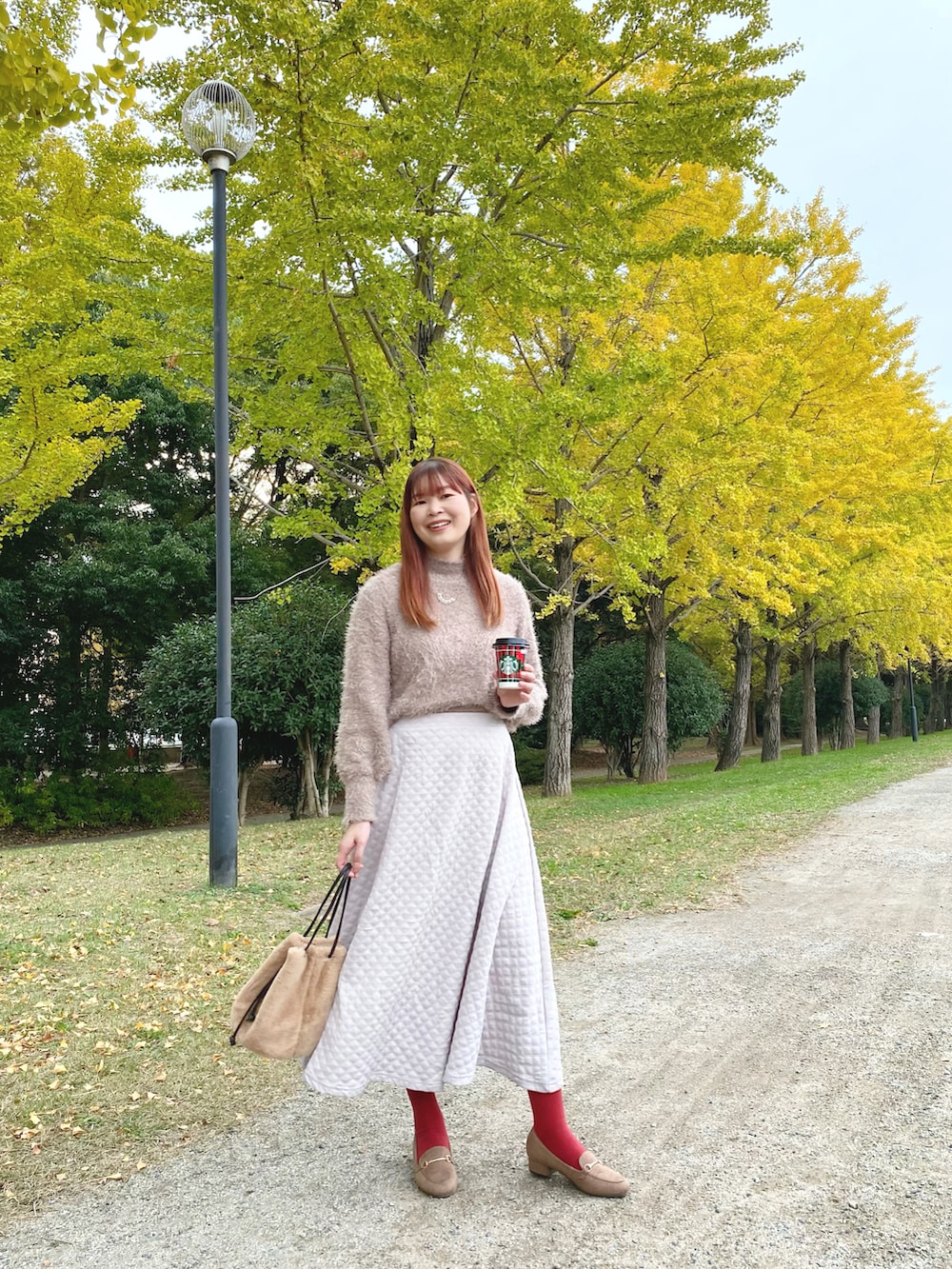 ホワイト系のスカート、ブラウン系のローファー、ブラウン系のニット/セーターを着用したレディースの秋コーディネートの2枚目の写真