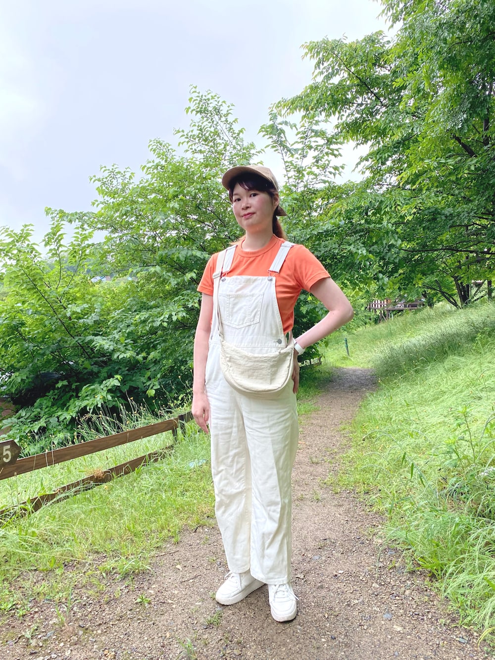 オレンジ系のTシャツ/カットソー、ホワイト系のサロペット/オーバーオール、ホワイト系のスニーカーを着用したレディースの春コーディネートの2枚目の写真