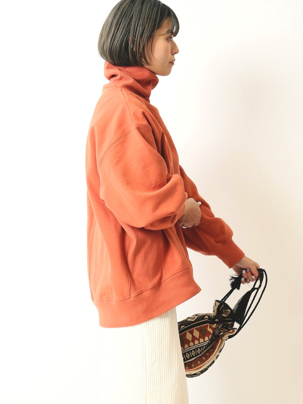 オレンジ系のTシャツ/カットソー、ホワイト系のスカート、オレンジ系のショルダーバッグを着用したレディースの秋コーディネートの5枚目の写真