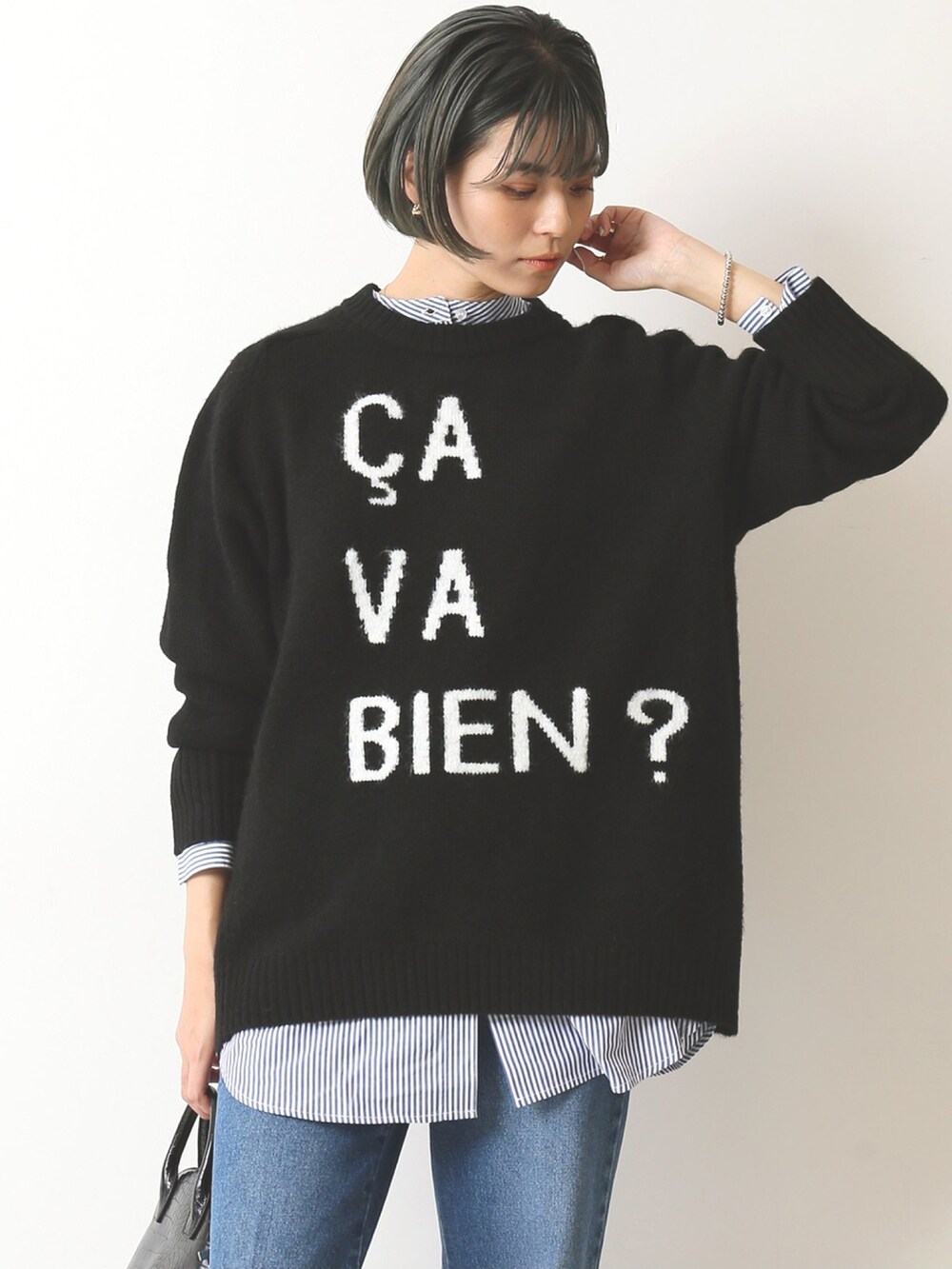 ブラック系のニット/セーター、ブルー系のデニムパンツを着用したレディースの秋コーディネートの4枚目の写真