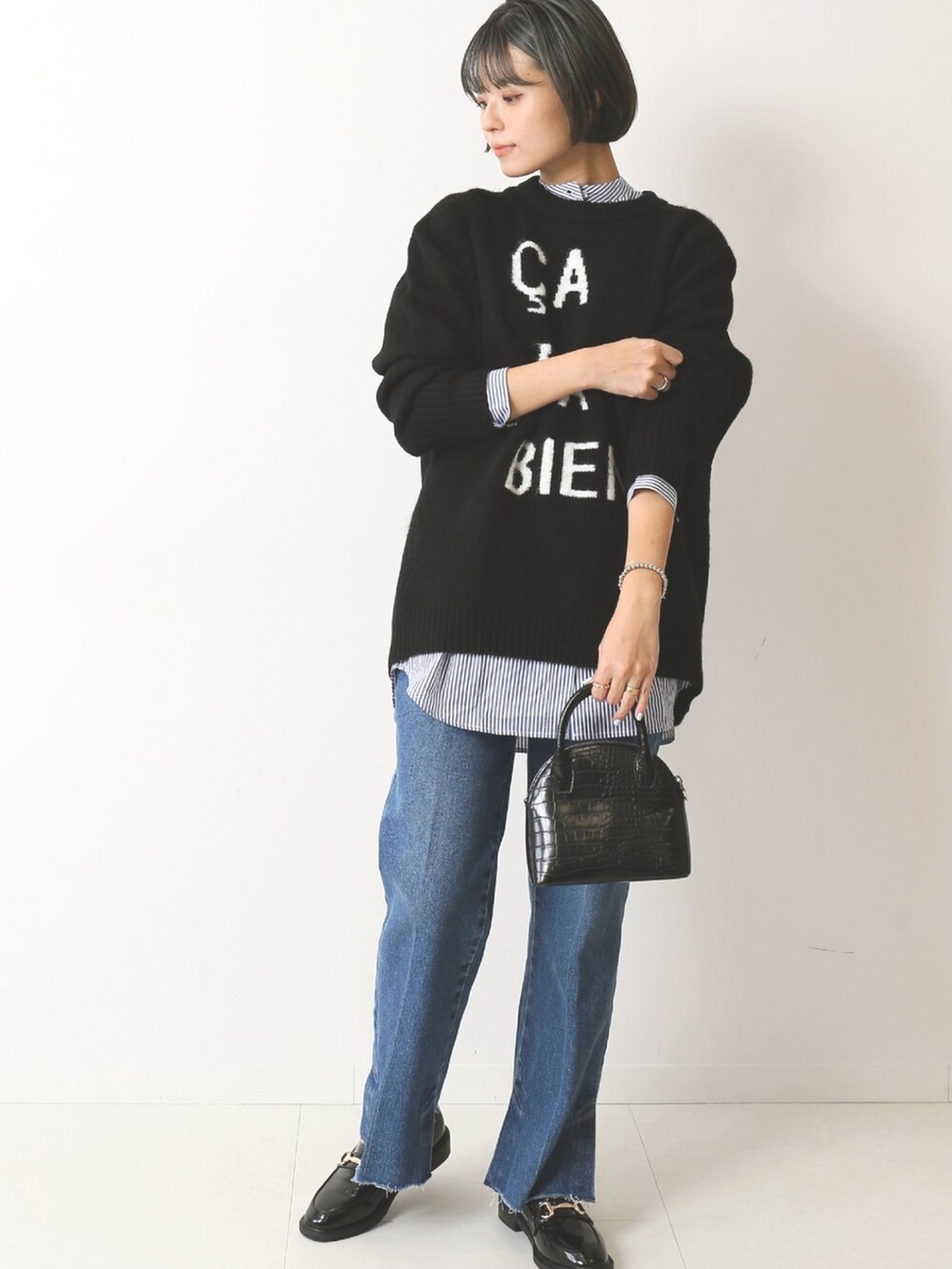 ブラック系のニット/セーター、ブルー系のデニムパンツを着用したレディースの秋コーディネートの2枚目の写真