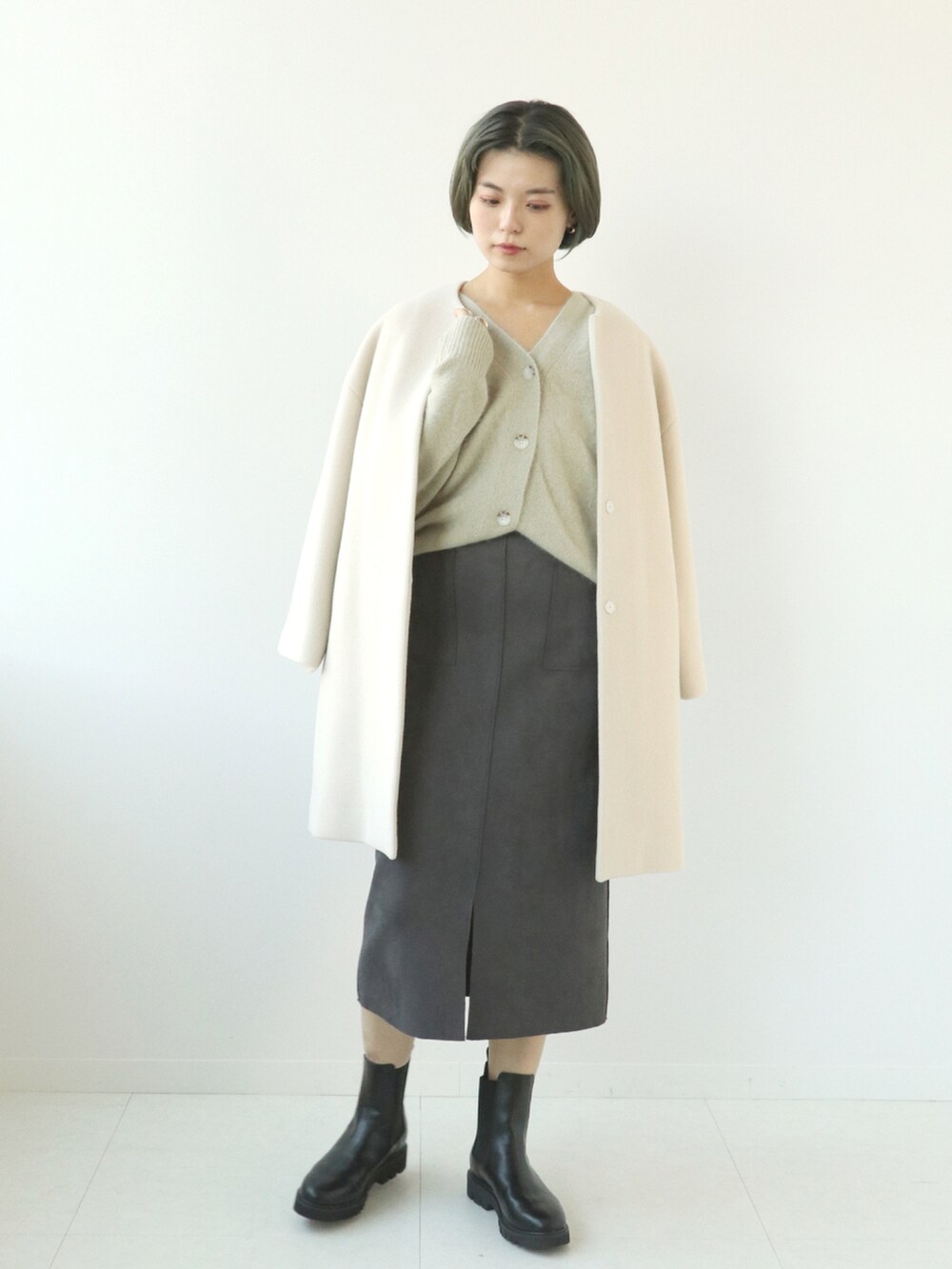 ホワイト系のノーカラーコート、ベージュ系のカーディガン/ボレロ、グレー系のスカートを着用したレディースの秋コーディネートの4枚目の写真