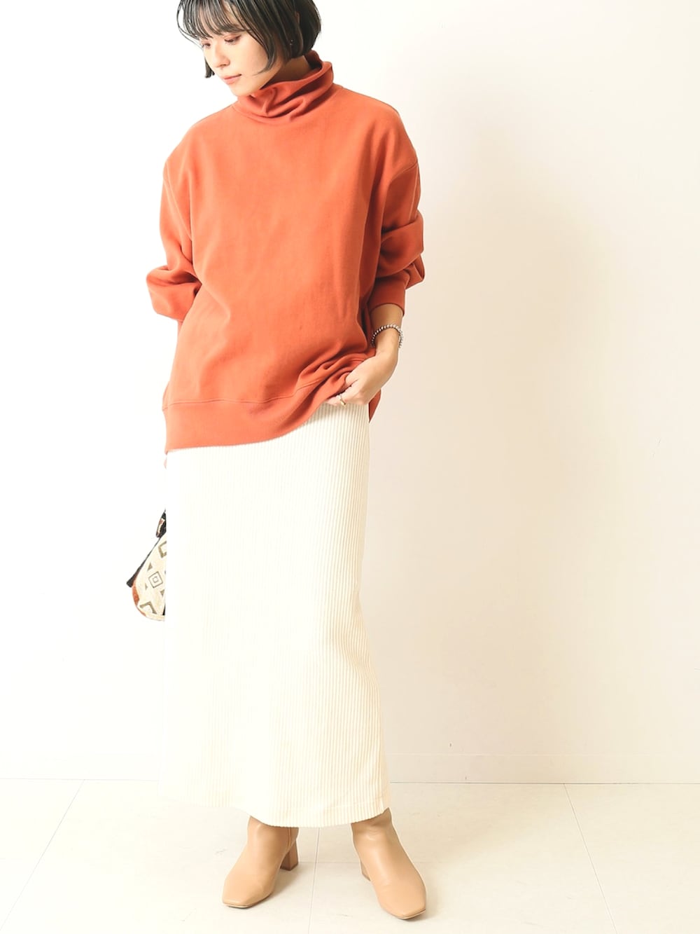 オレンジ系のTシャツ/カットソー、ホワイト系のスカート、オレンジ系のショルダーバッグを着用したレディースの秋コーディネートの2枚目の写真