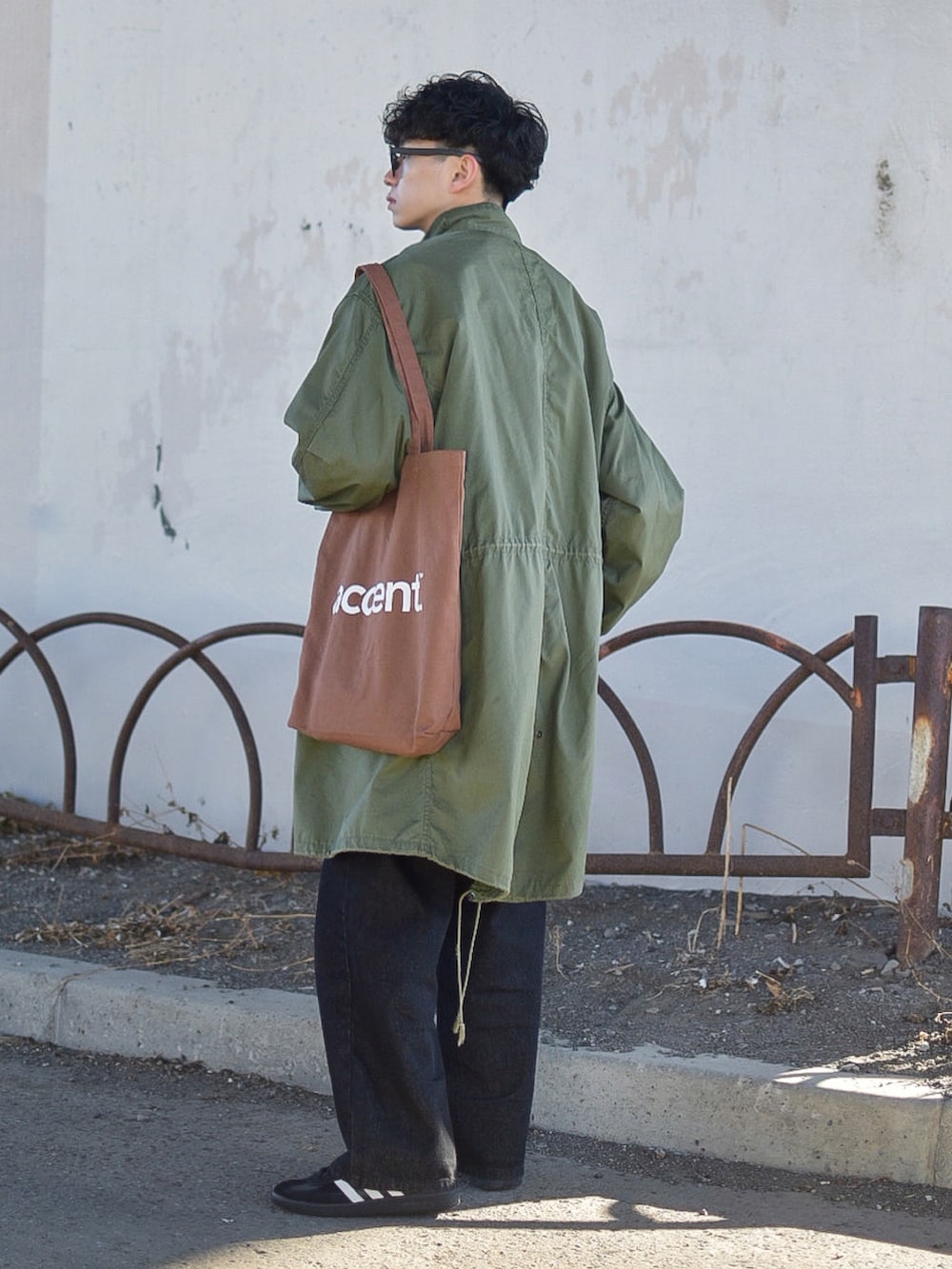 グリーン系のモッズコート、ブラック系のデニムパンツ、ブラック系のスニーカーを着用したメンズの冬コーディネートの4枚目の写真