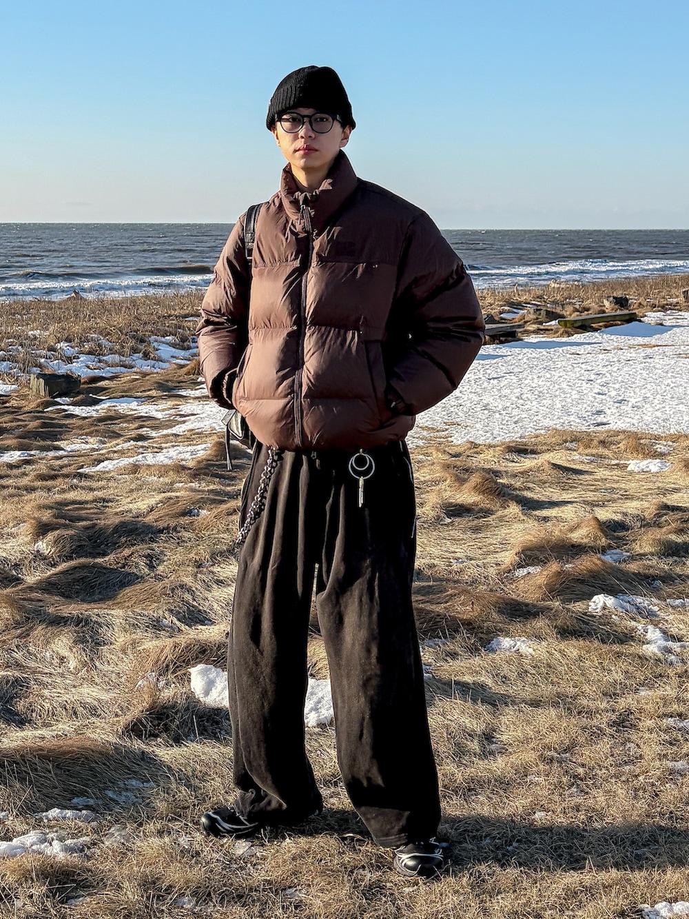 ブラウン系のダウンジャケット/コート、ブラック系のスウェットパンツ、ブラック系のスニーカーを着用したメンズの冬コーディネートの2枚目の写真