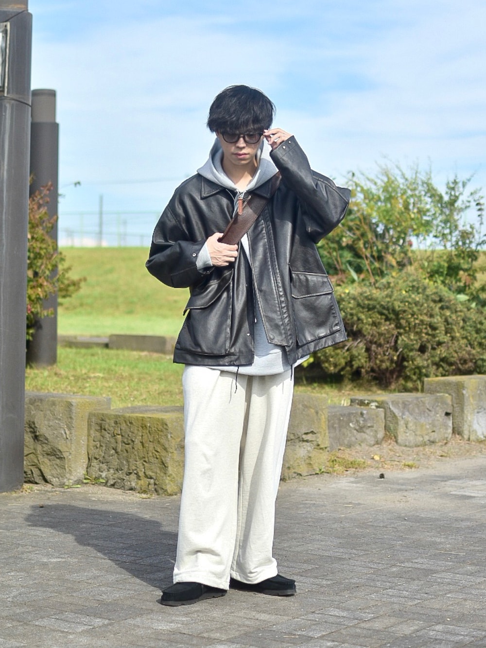 ブラック系のブルゾン、グレー系のパーカー、ホワイト系のスウェットパンツを着用したメンズの秋コーディネートの2枚目の写真