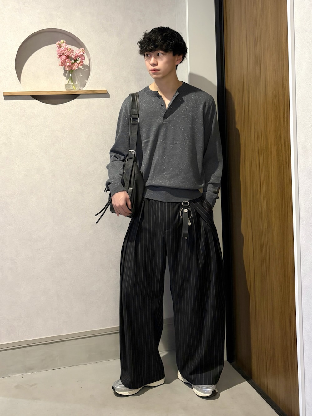 グレー系のニット/セーター、ブラック系のスラックス、シルバー系のスニーカーを着用したメンズの春コーディネートの2枚目の写真