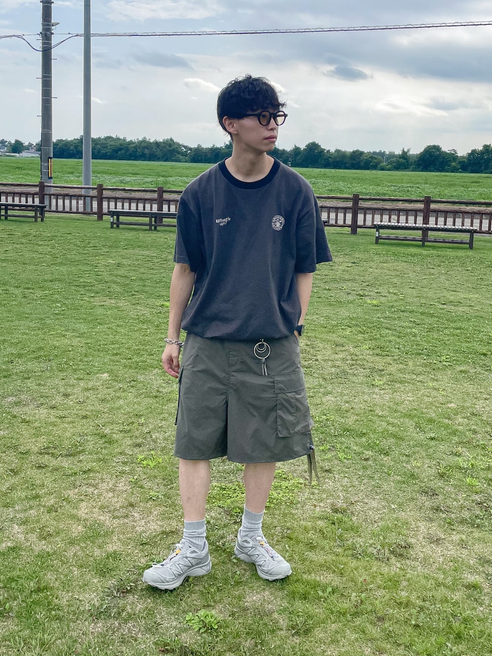 グリーン系のカーゴパンツ、ブラック系のTシャツ/カットソー、シルバー系のスニーカーを着用したメンズの夏コーディネートの2枚目の写真