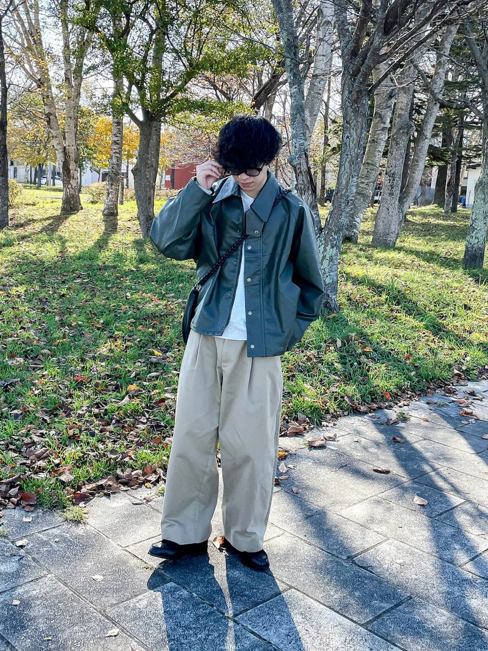 グリーン系のブルゾン、ベージュ系のスウェット、ブラック系のローファーを着用したメンズの秋コーディネートの3枚目の写真