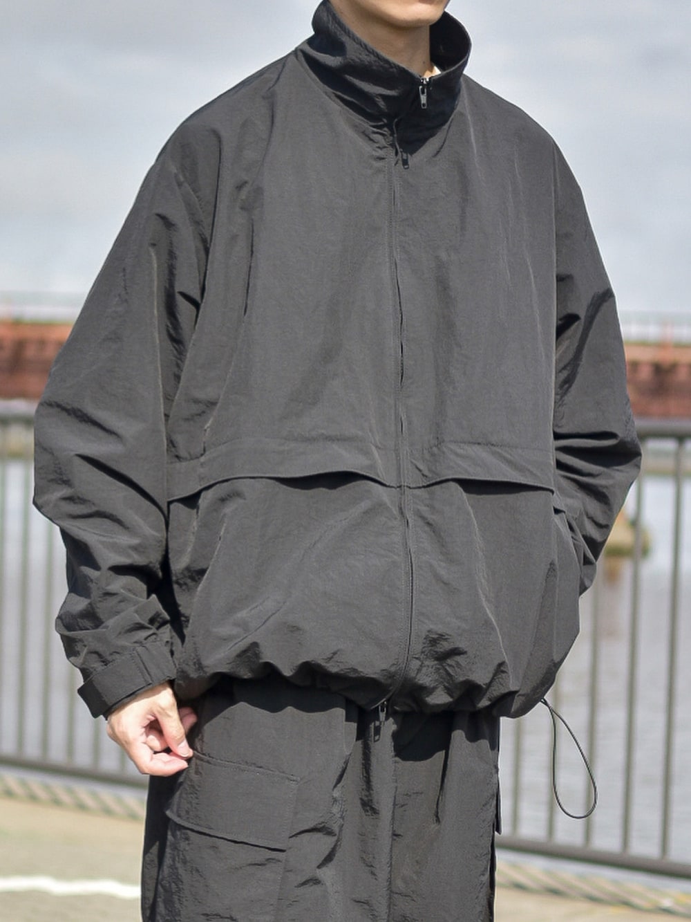 ブラック系のナイロンジャケット、ブラック系のカーゴパンツを着用したメンズの秋コーディネートの5枚目の写真