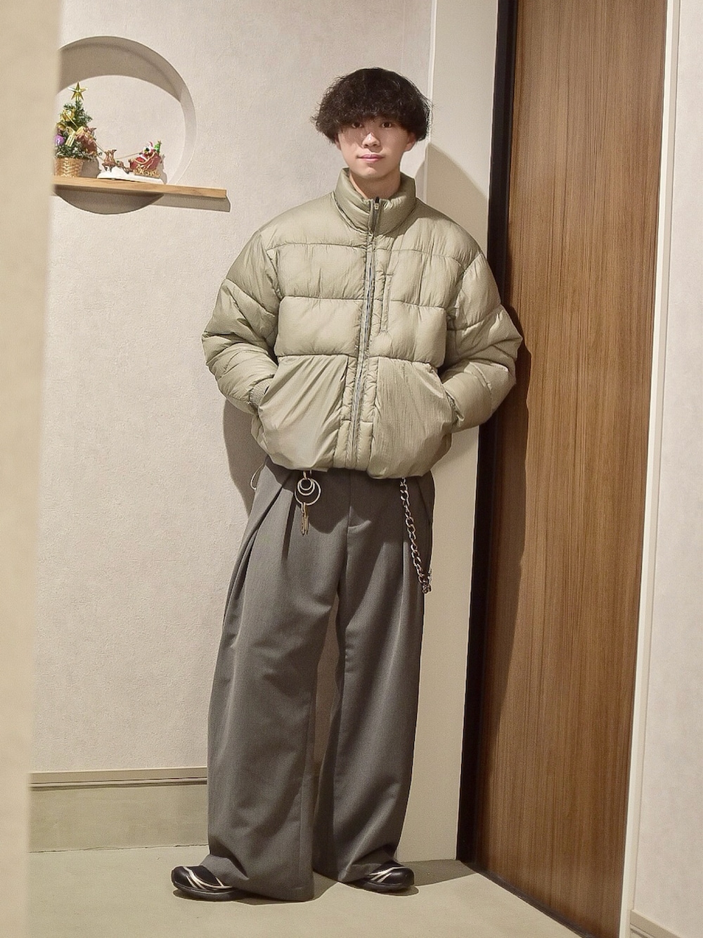 グレー系のスラックス、グレー系のダウンジャケット/コート、ブラック系のスニーカーを着用したメンズの冬コーディネートの2枚目の写真