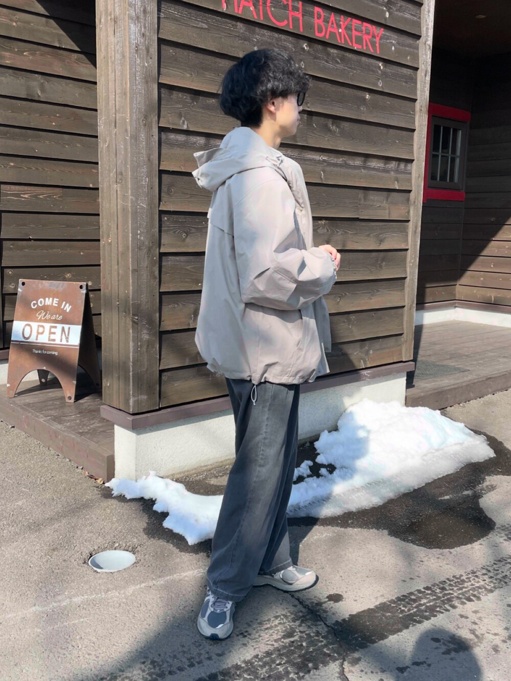 ベージュ系のマウンテンパーカー、グレー系のデニムパンツ、グレー系のスニーカーを着用したメンズの春コーディネートの2枚目の写真