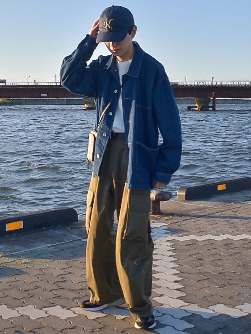 ブルー系のカバーオール、グリーン系のカーゴパンツ、ブラック系のシューズを着用したメンズの秋コーディネートの2枚目の写真