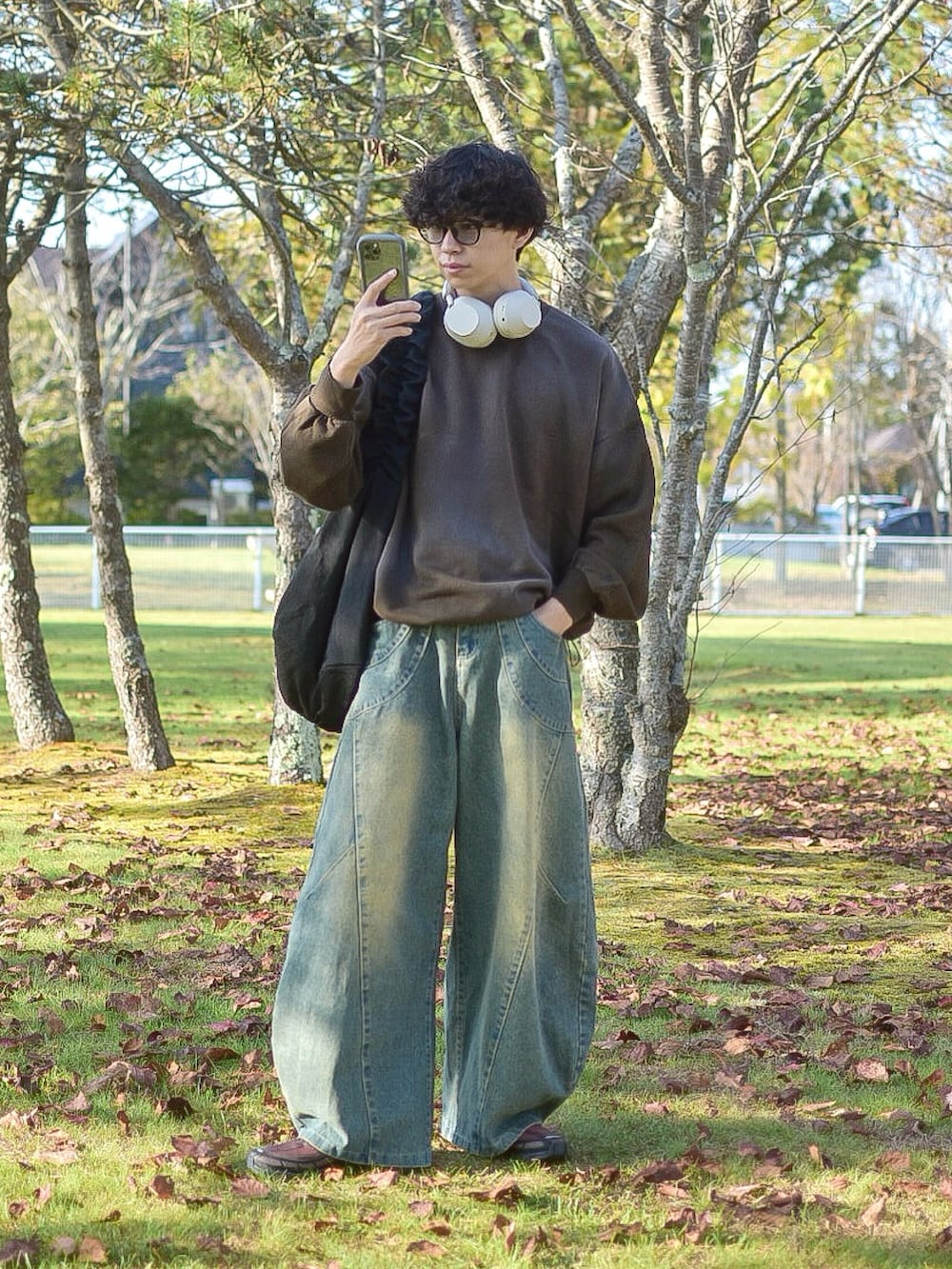 ブラウン系のスウェット、ブルー系のデニムパンツ、ブラック系のショルダーバッグを着用したメンズの秋コーディネートの2枚目の写真