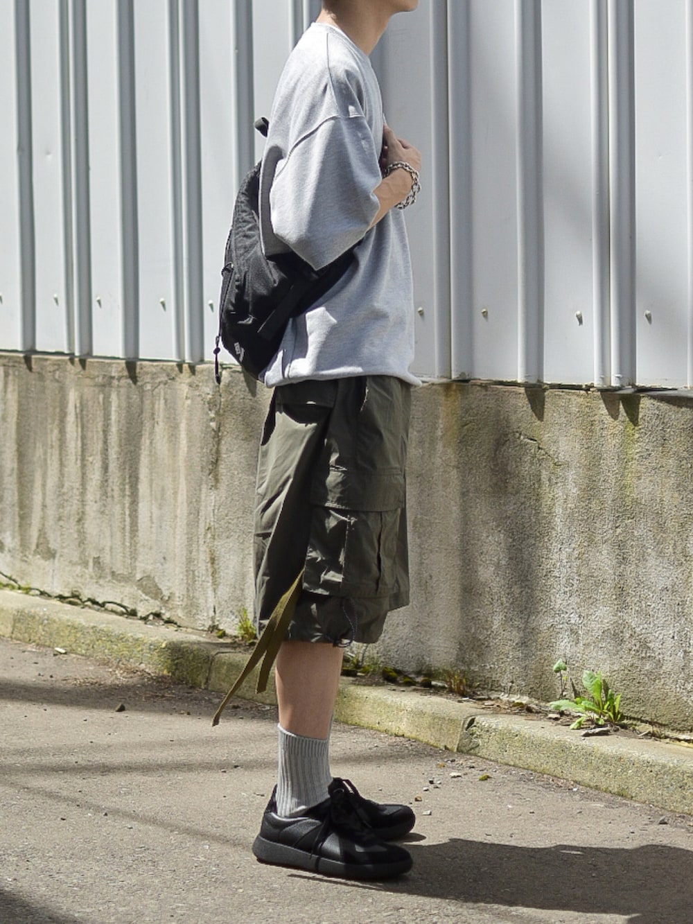 グレー系のTシャツ/カットソー、グリーン系のカーゴパンツ、ブラック系のスニーカーを着用したメンズの夏コーディネートの4枚目の写真