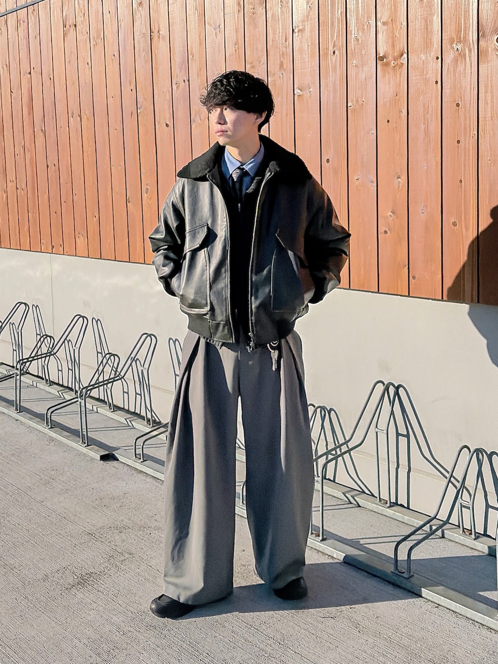 ブラック系のニット/セーター、ブルー系のシャツ/ブラウス、ブラック系のブルゾンを着用したメンズの冬コーディネートの3枚目の写真