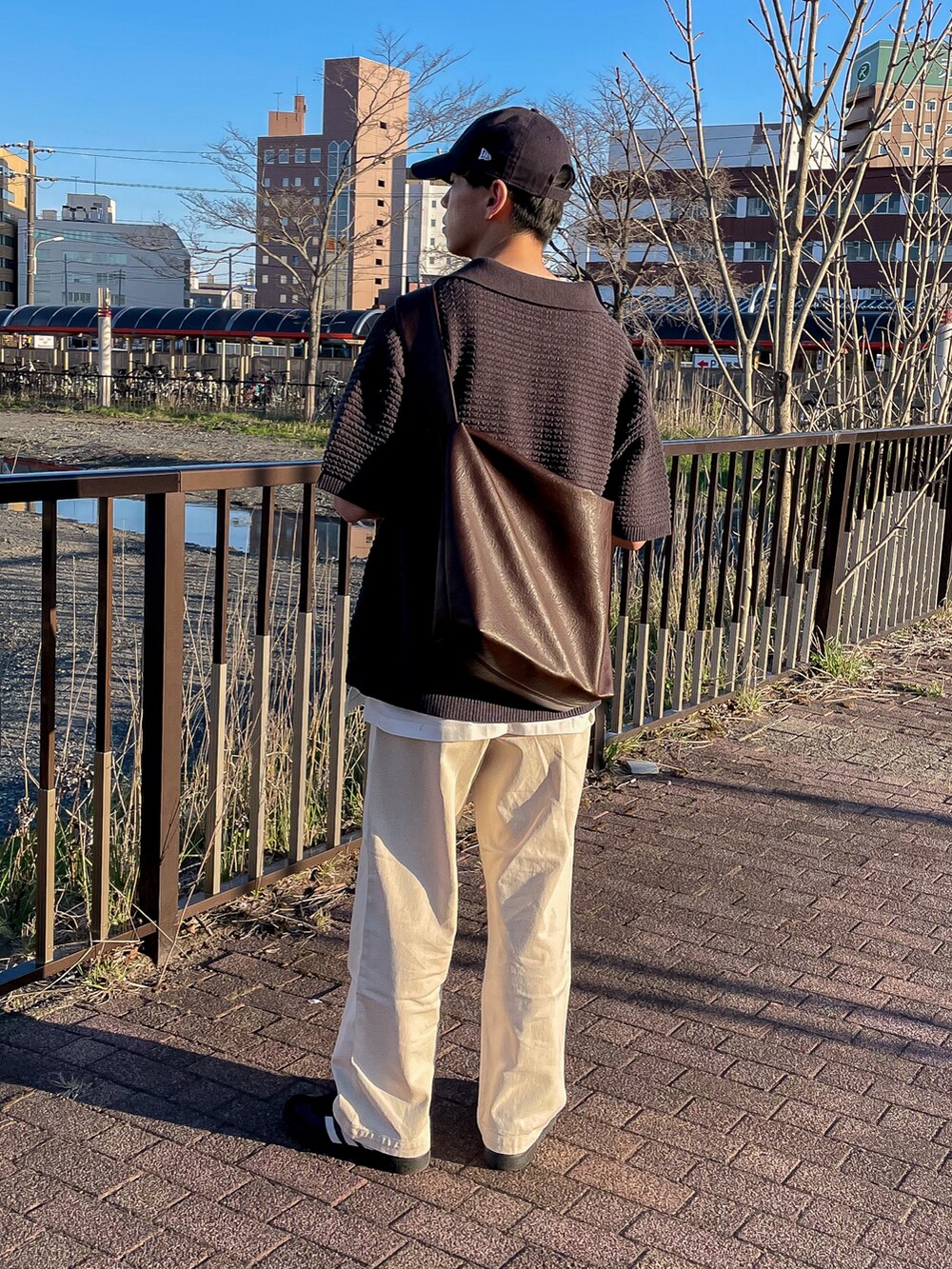 グレー系のポロシャツ、ホワイト系のタンクトップ、ホワイト系のデニムパンツを着用したメンズの春コーディネートの4枚目の写真