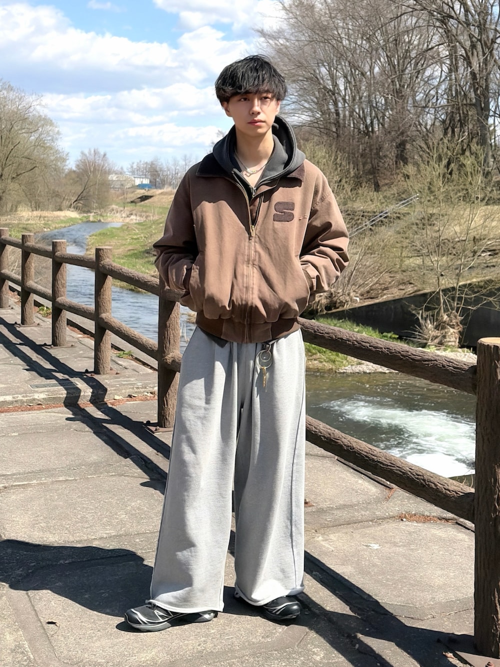 グレー系のパーカー、ブラウン系のブルゾン、グレー系のスウェットパンツを着用したメンズの春コーディネートの2枚目の写真