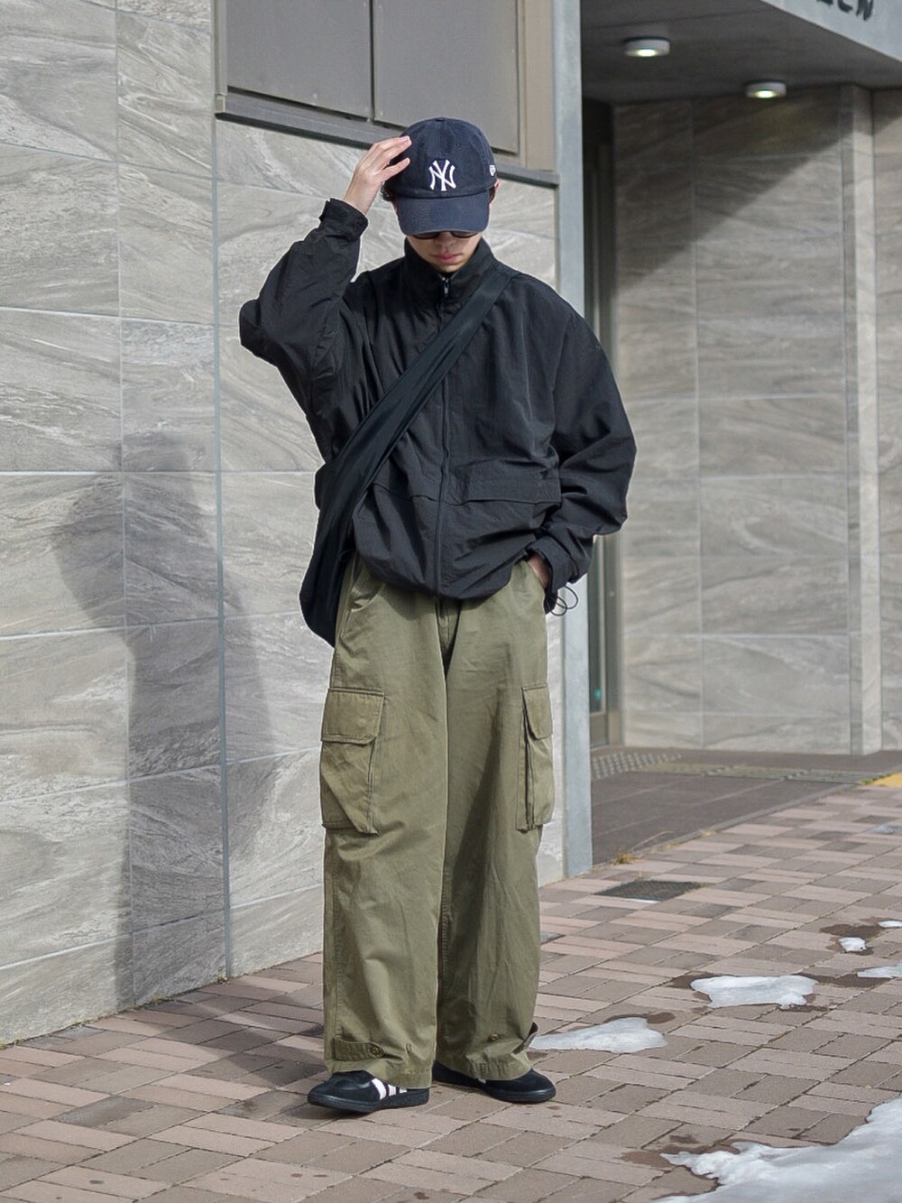 ブラック系のナイロンジャケット、グリーン系のカーゴパンツ、ブラック系のスニーカーを着用したメンズの冬コーディネートの3枚目の写真