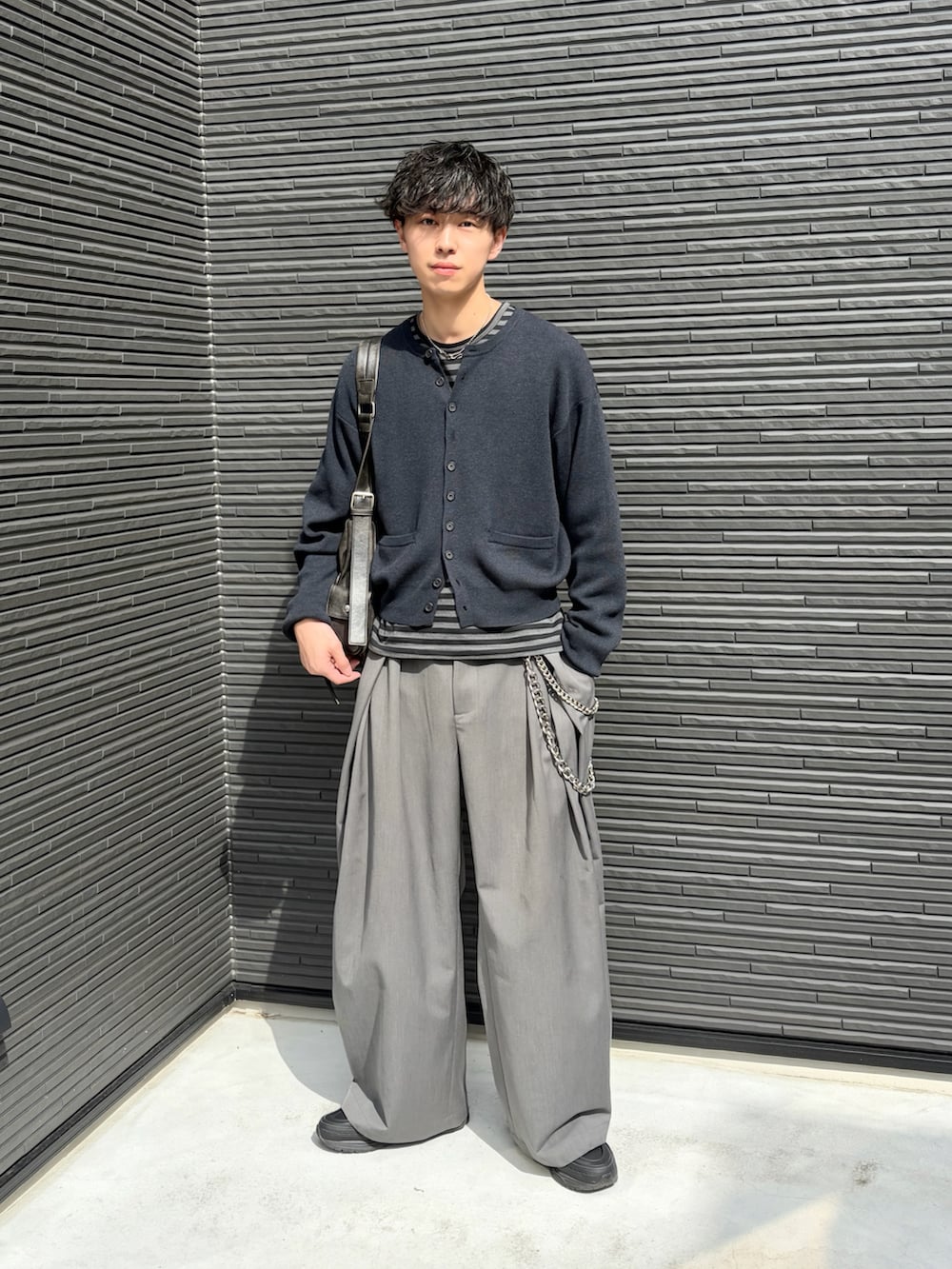 ブラック系のTシャツ/カットソー、ブラック系のカーディガン/ボレロ、グレー系のスラックスを着用したメンズの春コーディネートの2枚目の写真