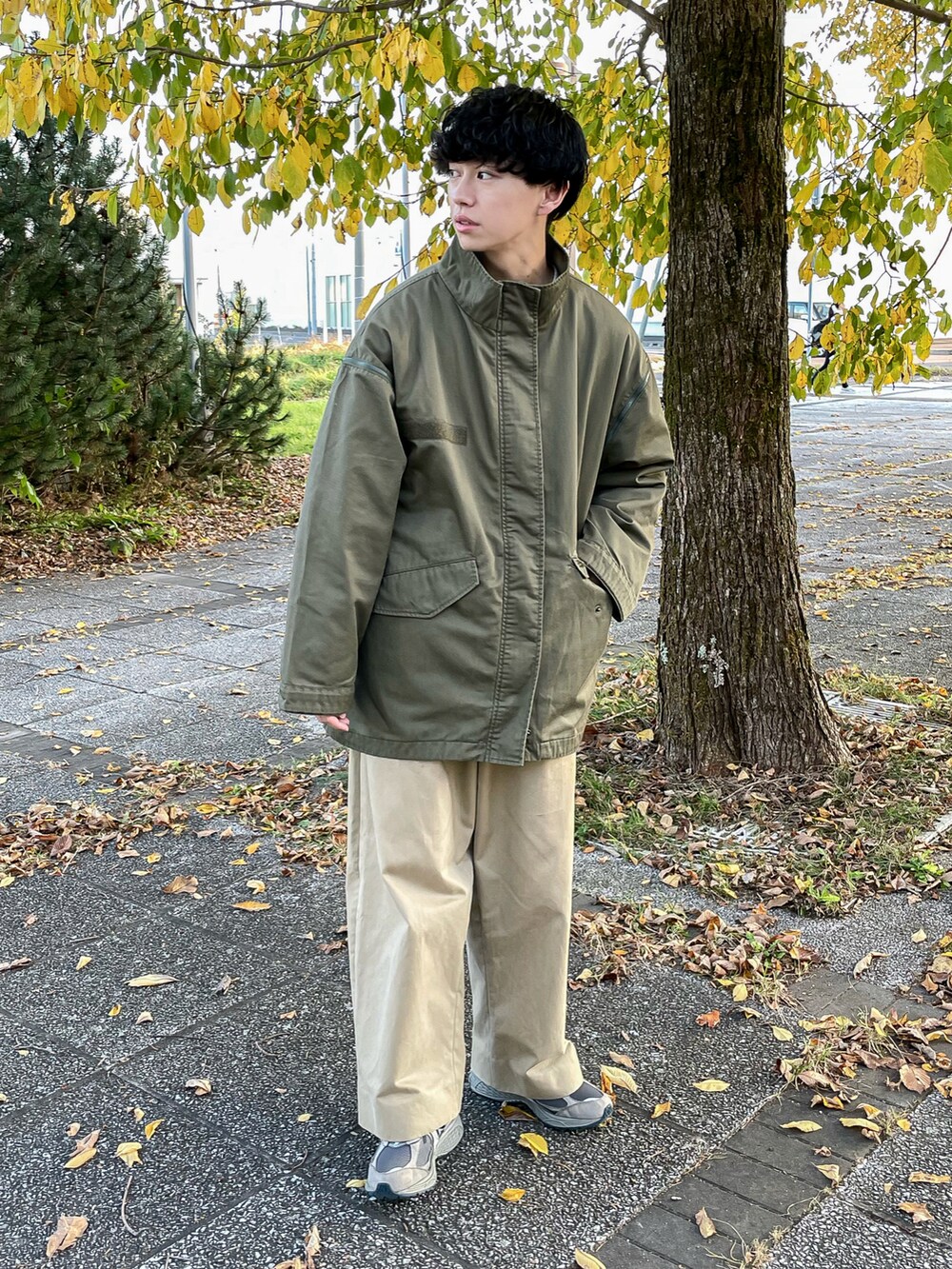 グリーン系のモッズコート、ホワイト系のスウェット、グレー系のスニーカーを着用したメンズの秋コーディネートの3枚目の写真