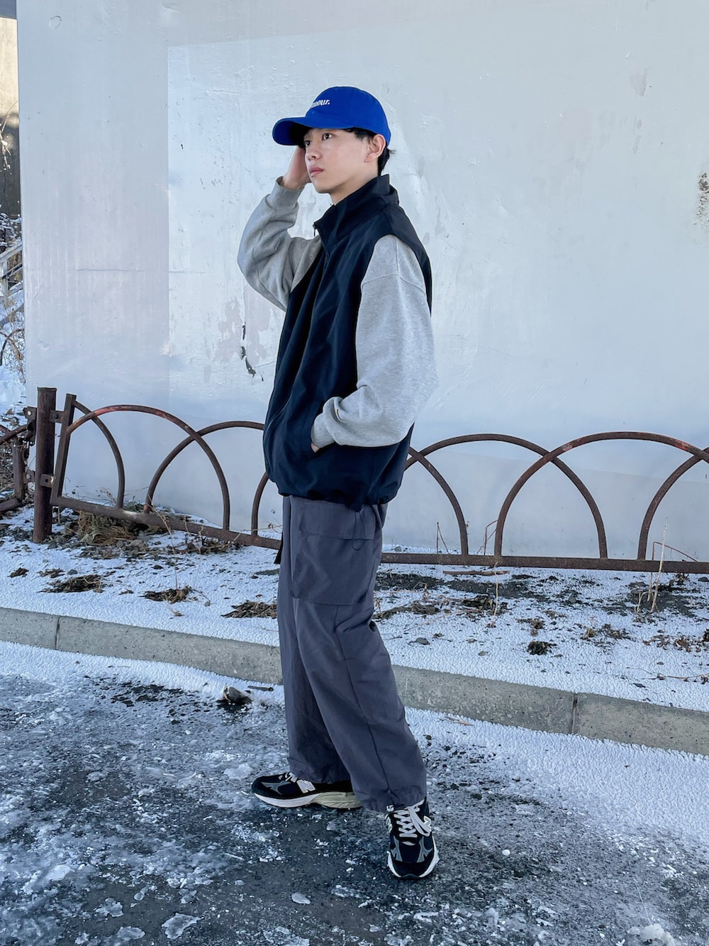 グレー系のカーゴパンツ、ブラック系のベスト、ブラック系のシューズを着用したメンズの冬コーディネートの3枚目の写真