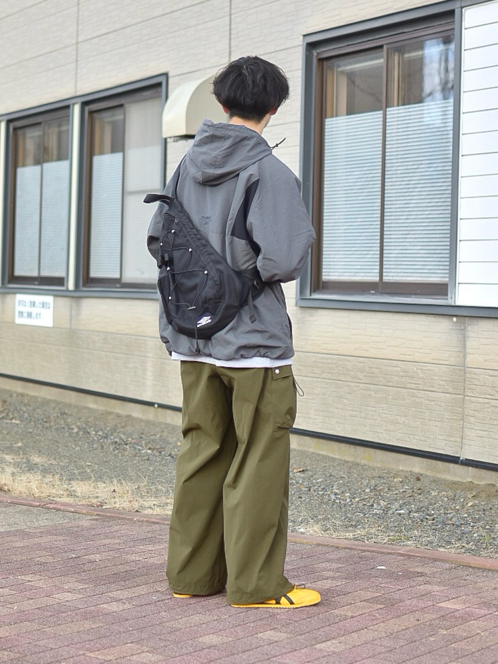 グレー系のナイロンジャケット、グレー系のスウェット、グリーン系のカーゴパンツを着用したメンズの秋コーディネートの3枚目の写真