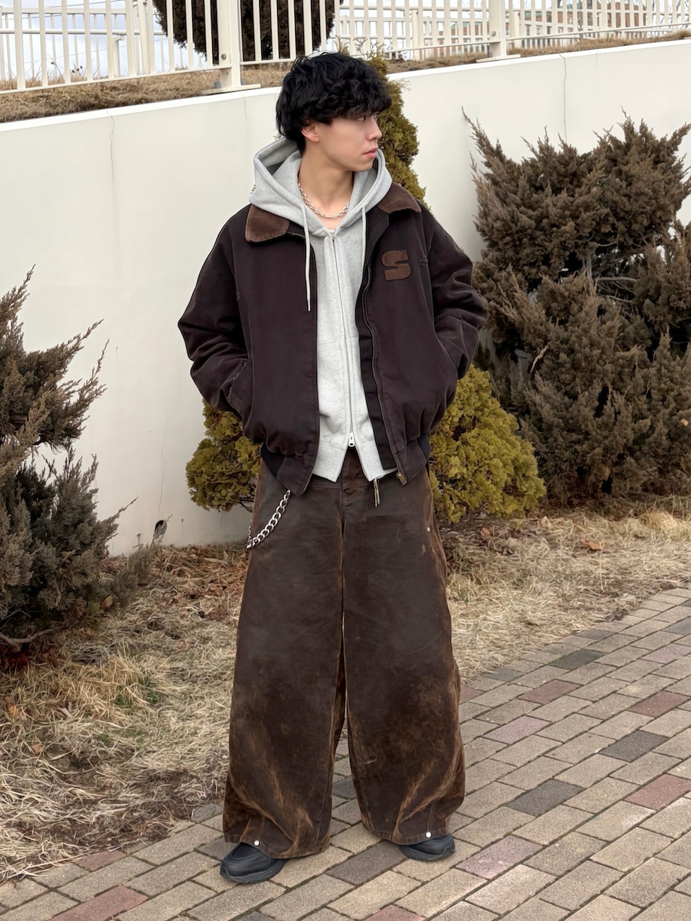 ブラック系のブルゾン、グレー系のパーカー、ブラウン系のデニムパンツを着用したメンズの春コーディネートの2枚目の写真