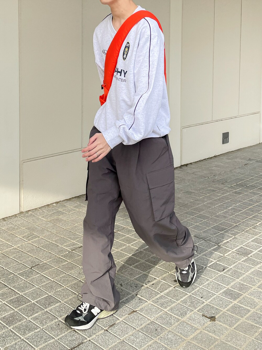 グレー系のスウェット、グレー系のカーゴパンツ、オレンジ系のショルダーバッグを着用したメンズの春コーディネートの5枚目の写真