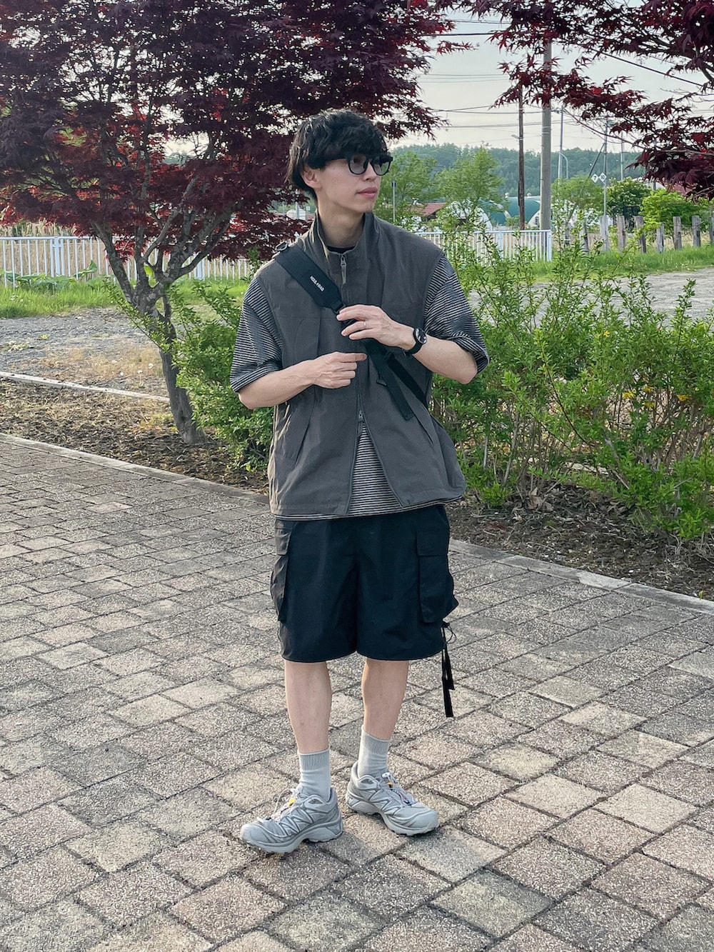 グレー系のベスト、グレー系のTシャツ/カットソー、シルバー系のスニーカーを着用したメンズの春コーディネートの2枚目の写真