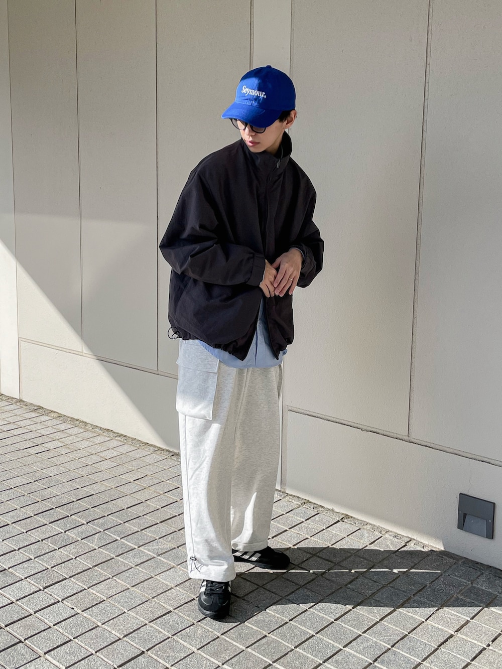 グレー系のナイロンジャケット、ブルー系のシャツ/ブラウス、ホワイト系のパンツを着用したメンズの冬コーディネートの2枚目の写真