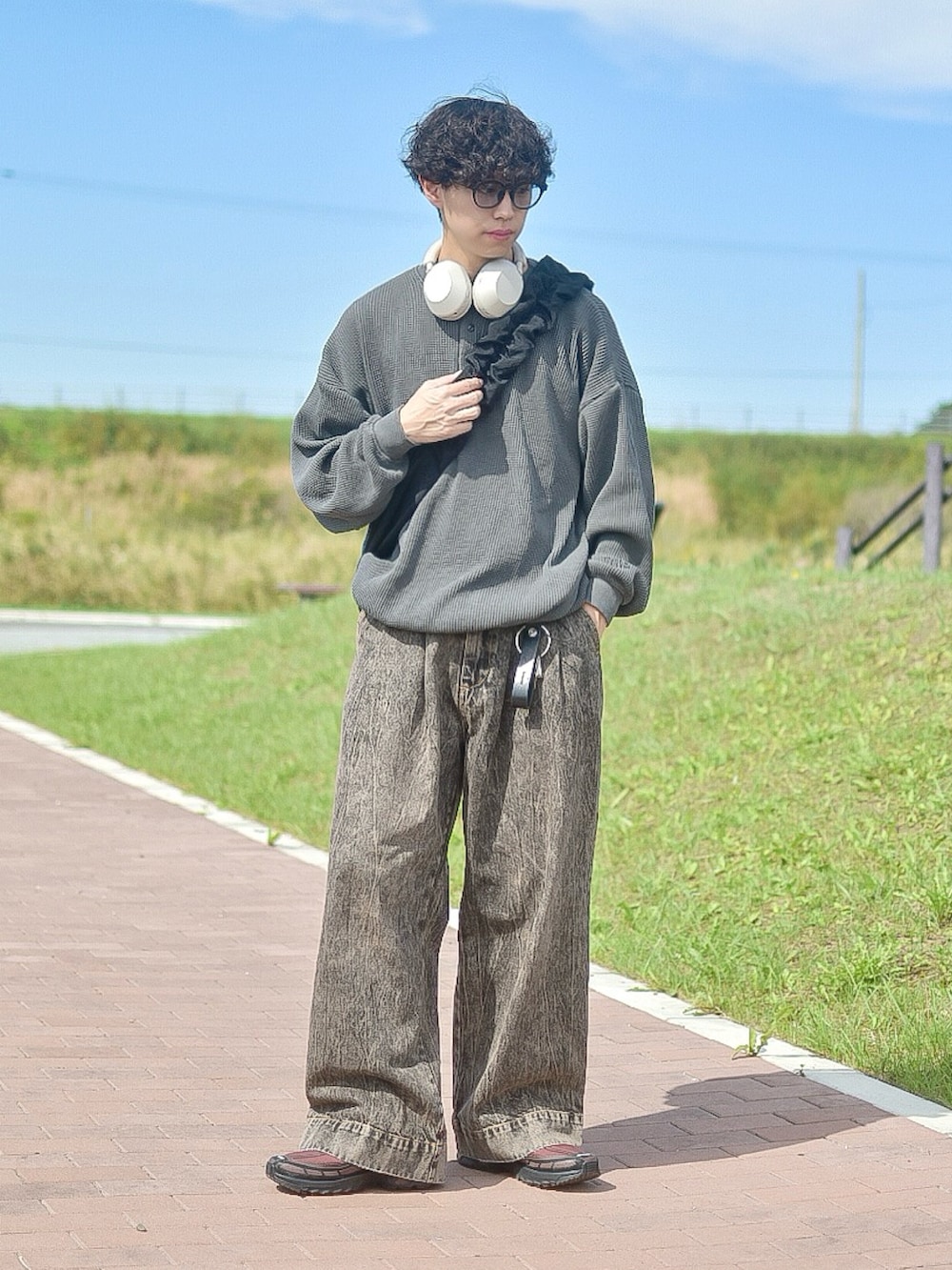 グレー系のTシャツ/カットソー、ブラウン系のデニムパンツ、ブラウン系のスニーカーを着用したメンズの秋コーディネートの3枚目の写真