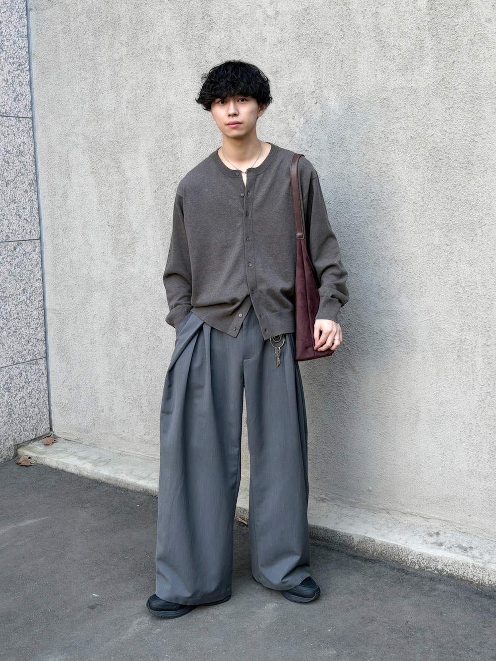 ブラウン系のカーディガン/ボレロ、グレー系のスラックス、ブラウン系のショルダーバッグを着用したメンズの春コーディネートの2枚目の写真