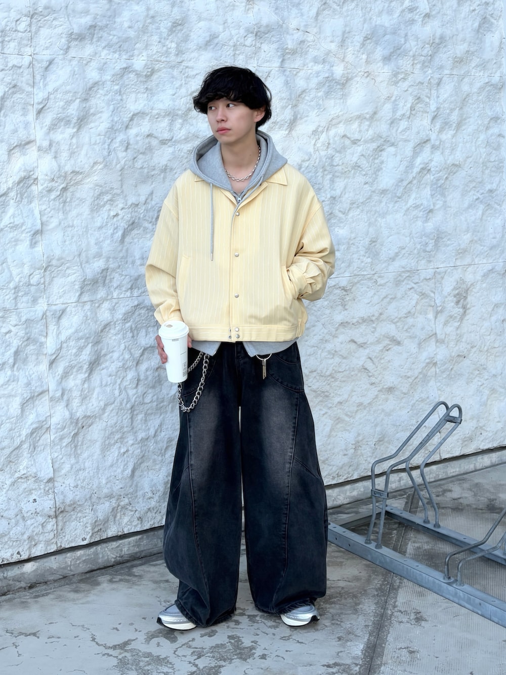 イエロー系のブルゾン、グレー系のパーカー、ブラック系のデニムパンツを着用したメンズの春コーディネートの5枚目の写真