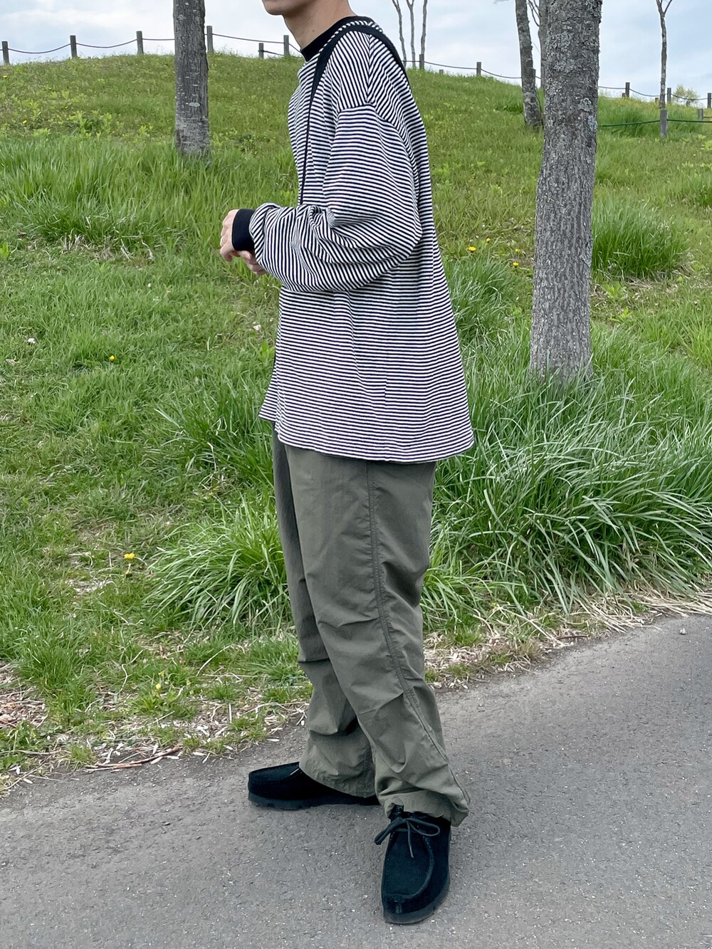 ブラック系のTシャツ/カットソー、グリーン系のパンツを着用したメンズの春コーディネートの4枚目の写真