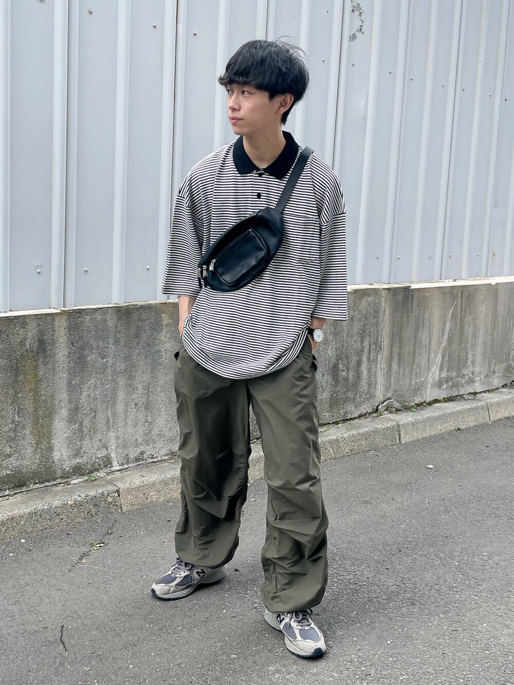 ブラック系のポロシャツ、ブラック系のボディバッグ/ウエストポーチ、グレー系のスニーカーを着用したメンズの夏コーディネートの2枚目の写真