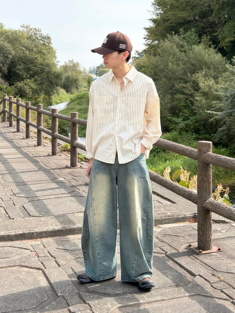 ブルー系のデニムパンツ、ブラウン系のスニーカー、イエロー系のシャツ/ブラウスを着用したメンズの秋コーディネートの2枚目の写真