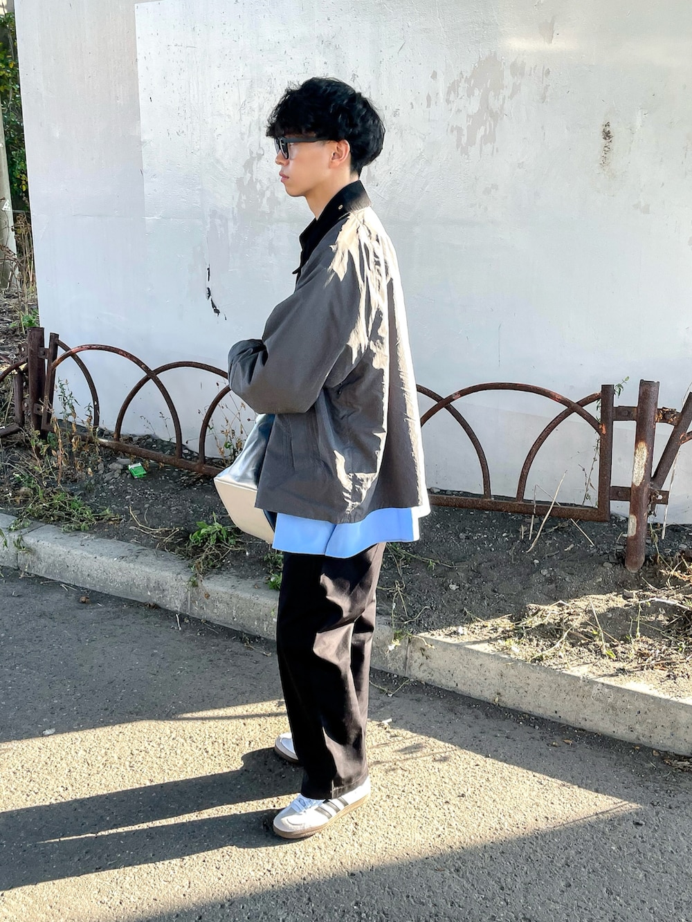 グレー系のナイロンジャケット、ブラック系のチノパンツ、ブルー系のシャツ/ブラウスを着用したメンズの秋コーディネートの3枚目の写真