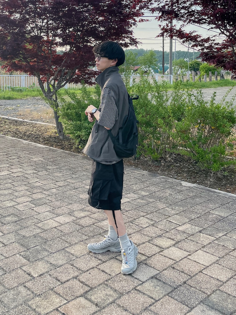 グレー系のベスト、グレー系のTシャツ/カットソー、シルバー系のスニーカーを着用したメンズの春コーディネートの4枚目の写真