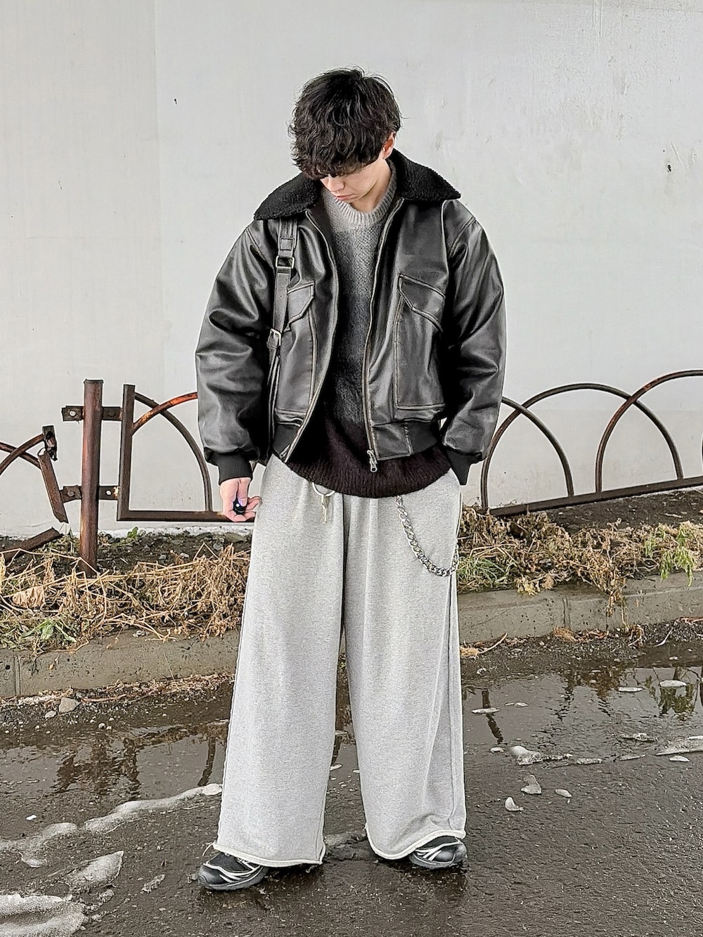 ブラック系のニット/セーター、ブラック系のブルゾン、グレー系のスウェットパンツを着用したメンズの冬コーディネートの2枚目の写真