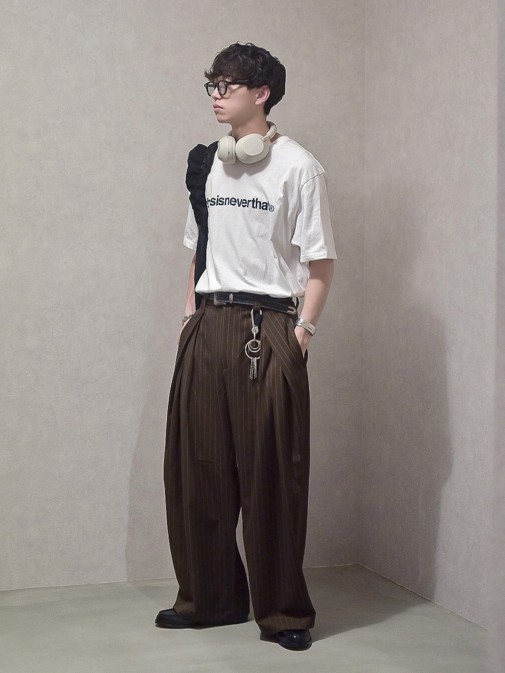 ブラウン系のスラックス、ブラック系のローファー、ホワイト系のTシャツ/カットソーを着用したメンズの春コーディネートの3枚目の写真